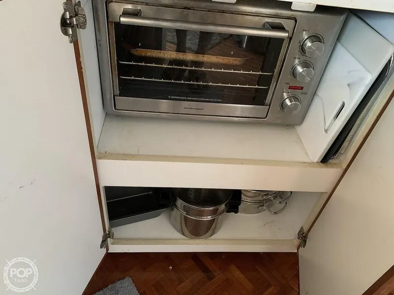 Slide: The Image of 1994 Cruisers Yachts Express Bridge kitchen storage with toaster oven and cookware. - 35