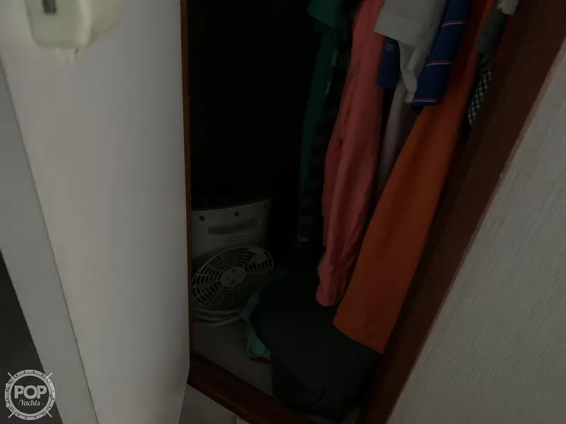 Slide: The Image of Small closet with hanging clothes and a fan inside a 1994 Cruisers Yachts Express Bridge. - 43