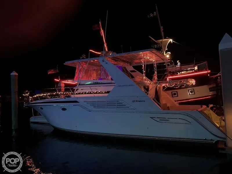 The Image of 1994 Cruisers Yachts Express Bridge illuminated at night, docked with festive lights. - 0