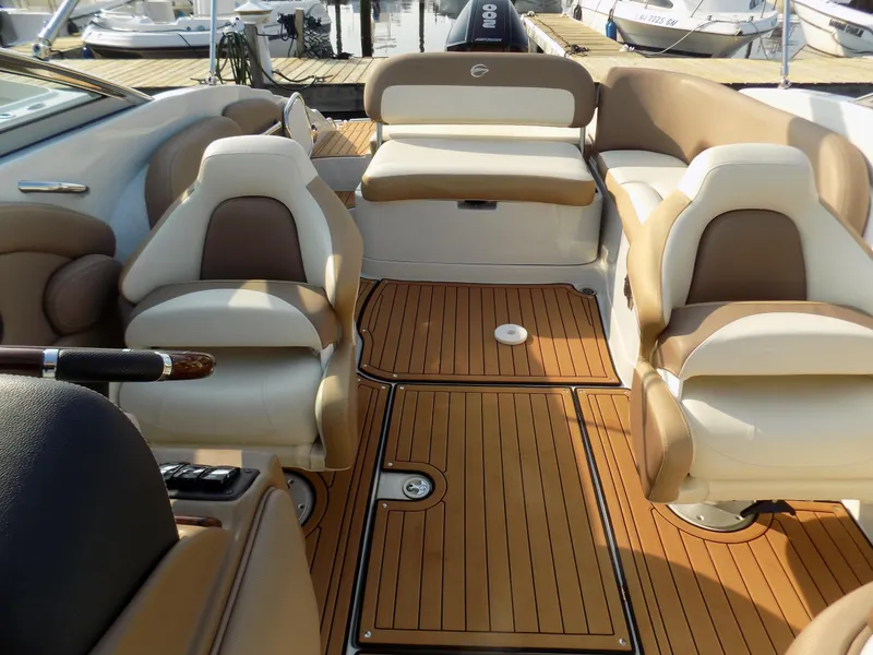 Slide: The Image of 2020 Crownline Eclipse E235 XS boat interior with tan and white seating, wooden flooring. - 6