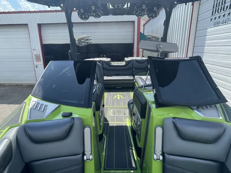 Slide: The Image of 2016 Malibu M235 boat interior with green and black seating, docked near storage units. - 7