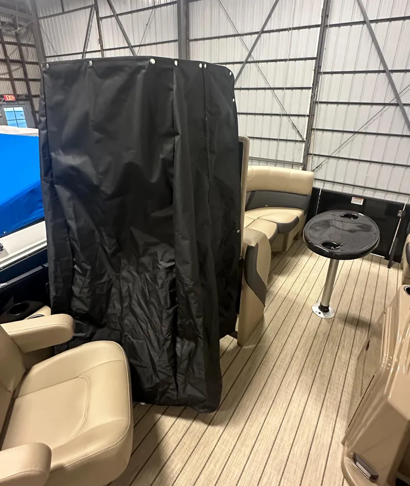 Slide: The Image of 2025 Sylvan MIRAGE X1 CLZ DH boat interior with seating and table in a storage facility. - 13