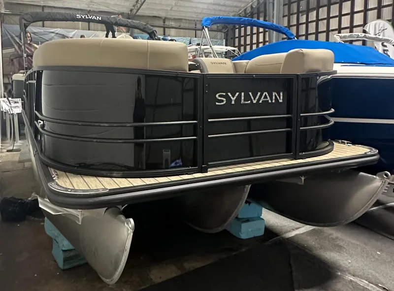 Slide: The Image of 2025 Sylvan MIRAGE X1 CLZ DH pontoon boat in storage, black exterior, beige seating. - 2