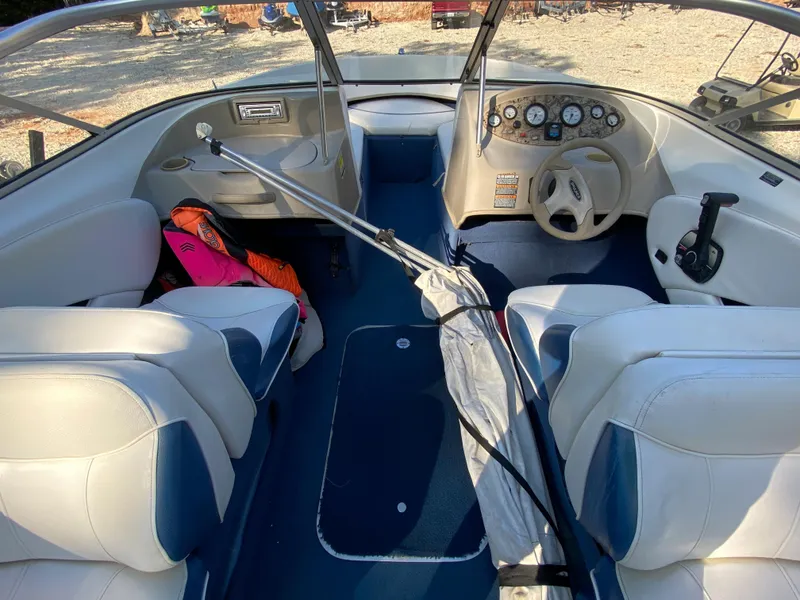 Slide: The Image of 2001 Bayliner 215 Bowrider interior with white and blue seating, steering wheel, and dashboard. - 12