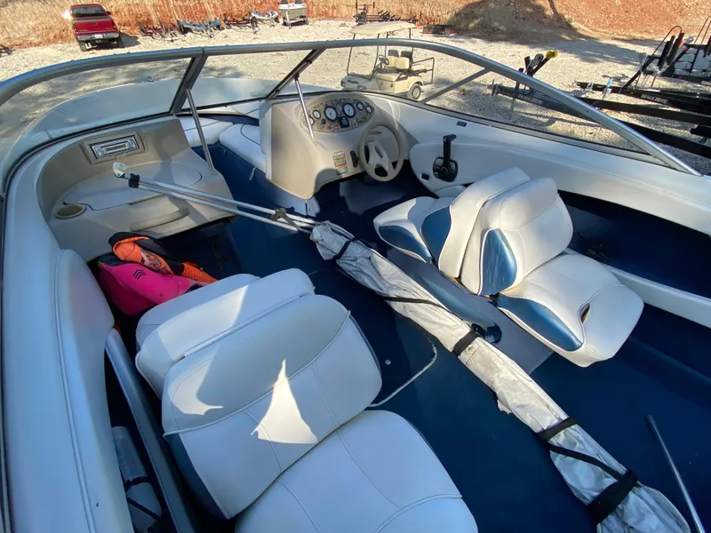 Slide: The Image of 2001 Bayliner 215 Bowrider interior with white and blue seating, steering console, and accessories. - 13
