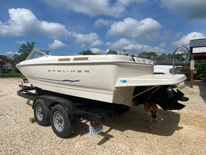 Slide: The Image of 2001 Bayliner 215 Bowrider on trailer, parked outdoors under a partly cloudy sky. - 32