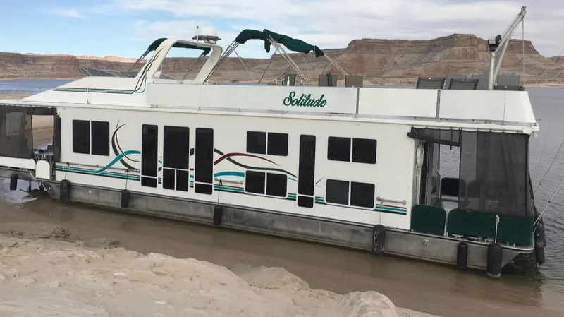 The Image of Houseboat "Solitude" by Horizon, docked on a sandy shore, under a partly cloudy sky. - 0