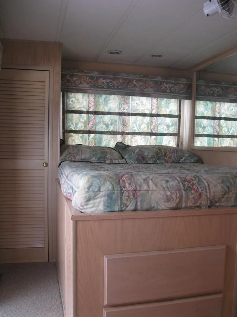 Slide: The Image of Cozy RV bedroom interior with floral bedding, wooden cabinets, and large windows. Horizon model, 2000. - 7