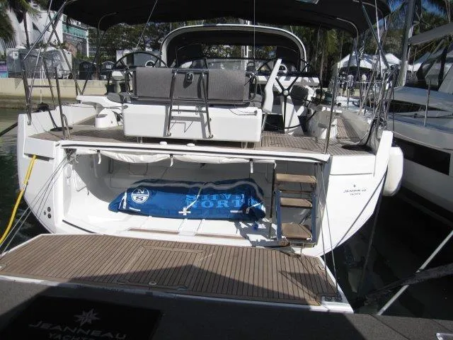 Slide: The Image of 2025 Jeanneau Yacht 65, rear view at dock, showcasing deck and seating area. - 14