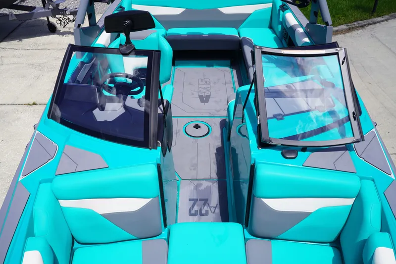 Slide: The Image of 2022 Axis A22 boat interior with turquoise and gray seating, open windshield, and steering wheel. - 28