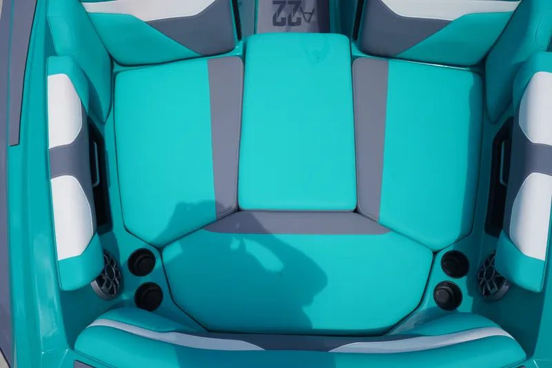 Slide: The Image of 2022 Axis A22 boat interior with teal and gray seating, cup holders, and speakers. - 27