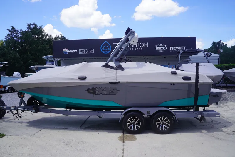 Slide: The Image of 2022 Axis A22 boat on trailer, covered, parked at dealership under blue sky. - 37