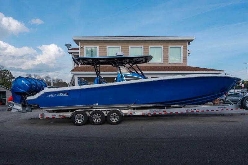 The Image of 2024 Nor-Tech 390 Center Console boat on a trailer, blue hull, triple engines. - 0
