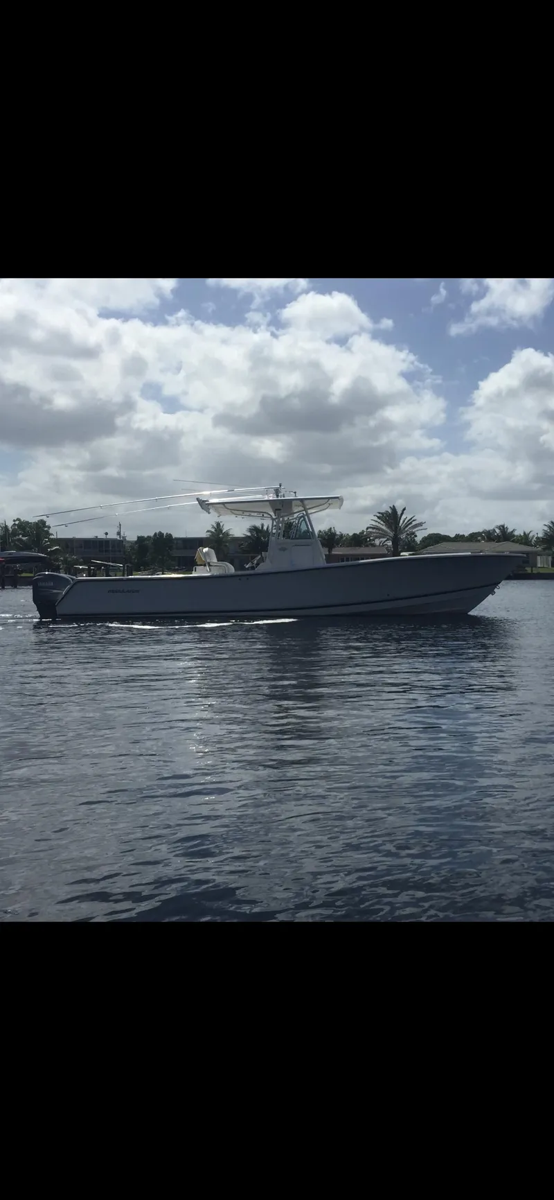 Slide: The Image of 2002 Regulator 32 Forward Seating boat on calm water under cloudy sky. - 28