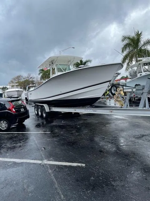 Slide: The Image of 2002 Regulator 32 Forward Seating boat on trailer in parking lot, cloudy sky. - 3