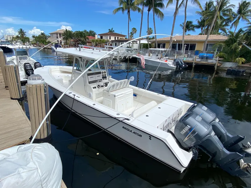 Slide: The Image of 2002 Regulator 32 Forward Seating boat docked by palm trees and waterfront homes. - 5