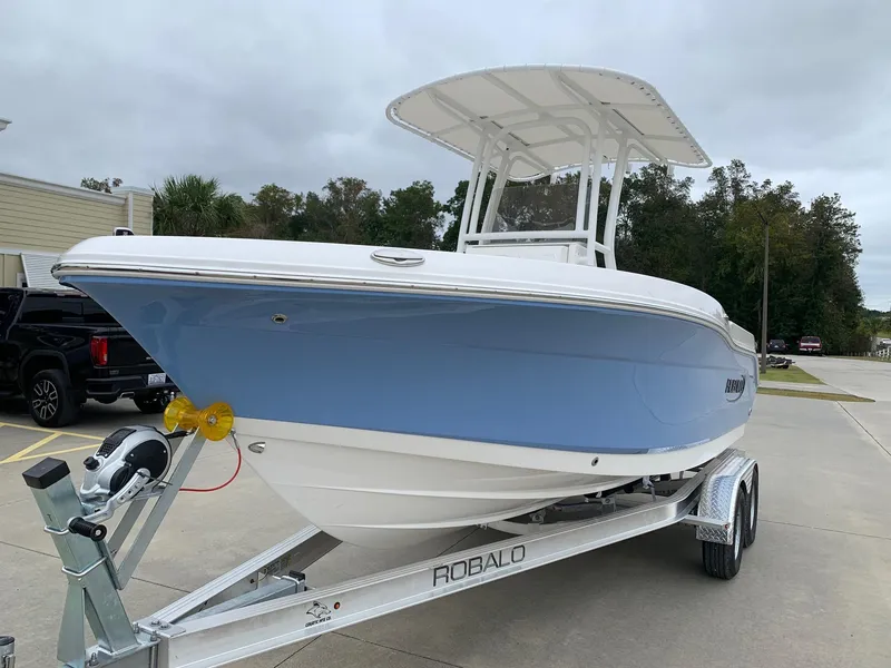 Slide: The Image of 2026 Robalo R200 Center Console boat on trailer, light blue hull, parked outdoors. - 2