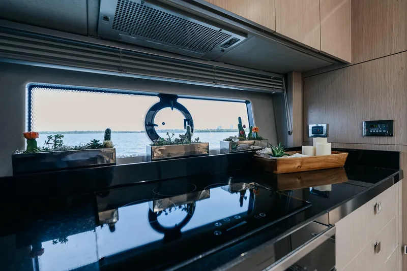 Slide: The Image of 2018 Sunseeker Predator 68 yacht kitchen with sleek black countertops and ocean view. - 27