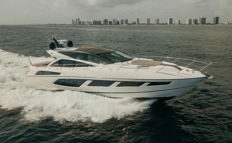 Slide: The Image of 2018 Sunseeker Predator 68 yacht cruising on the ocean near a city skyline. - 6