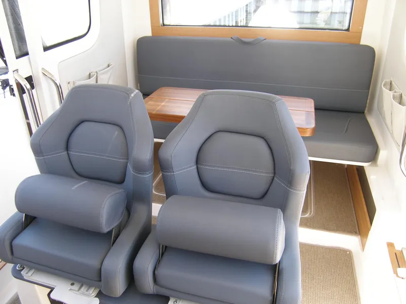 Slide: The Image of Interior seating of 2025 Nimbus C9 boat with grey cushioned seats and wooden table. - 2