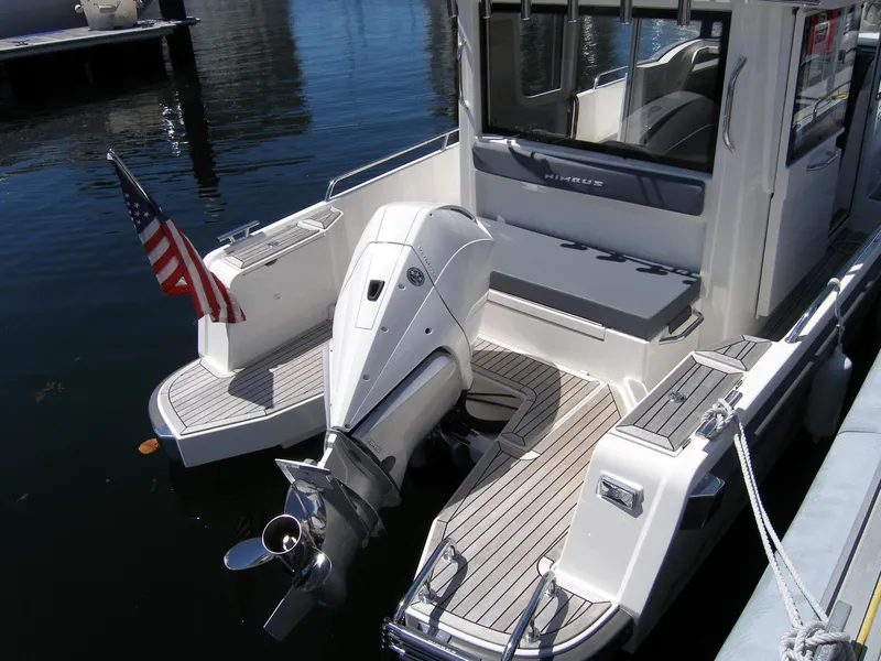 Slide: The Image of Nimbus C9 2025 boat with outboard motor, docked, rear view, American flag. - 4