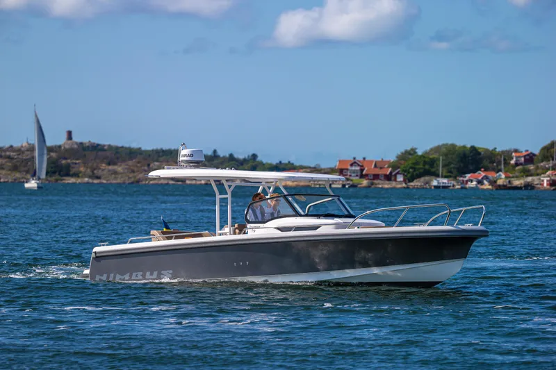 Slide: The Image of 2025 Nimbus T9 boat cruising on a scenic lake with houses in the background. - 13
