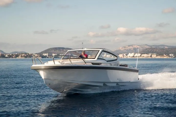 Slide: The Image of 2025 Nimbus W9 boat cruising on open water with scenic coastal background. - 16