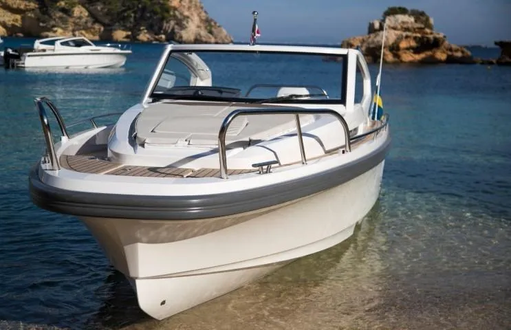 Slide: The Image of 2025 Nimbus W9 boat docked in clear blue water near rocky shore. - 9