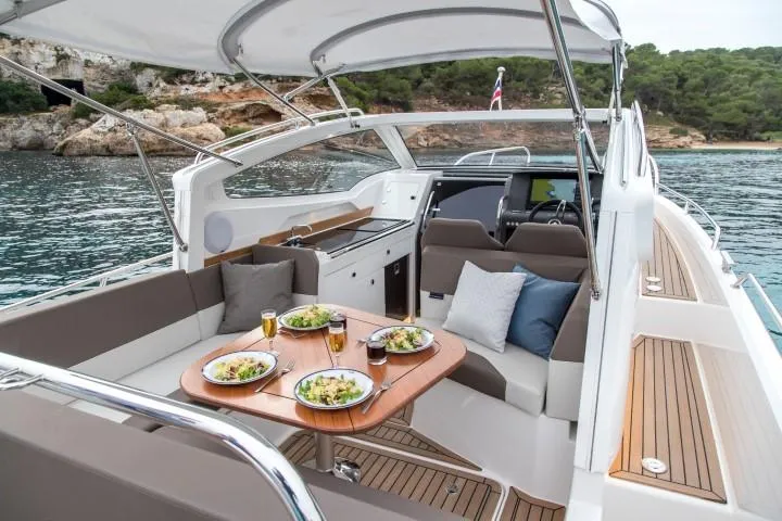Slide: The Image of Nimbus W9 2025 luxury yacht with dining setup on deck, anchored in scenic bay. - 29
