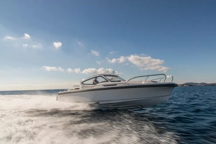 Slide: The Image of 2025 Nimbus W9 boat speeding on open water under a clear sky. - 18