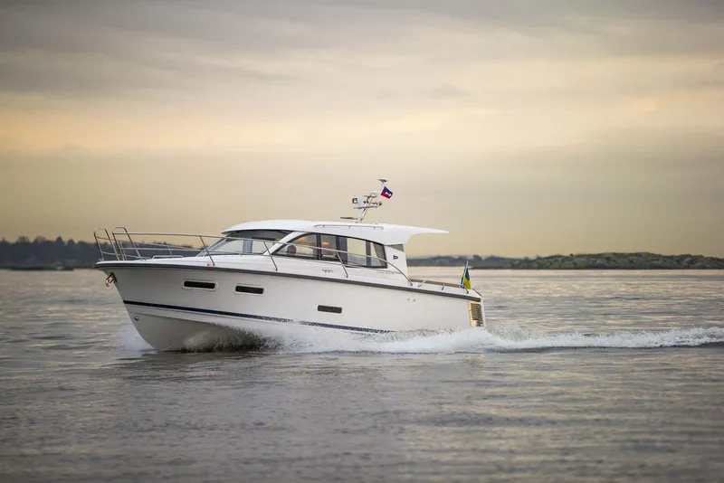 Slide: The Image of 2024 Nimbus 305 Coupe cruising on calm waters at sunset. - 0
