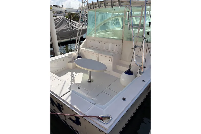 Slide: The Image of 2003 Cabo 45 Express boat deck with seating and table, docked in marina. - 6