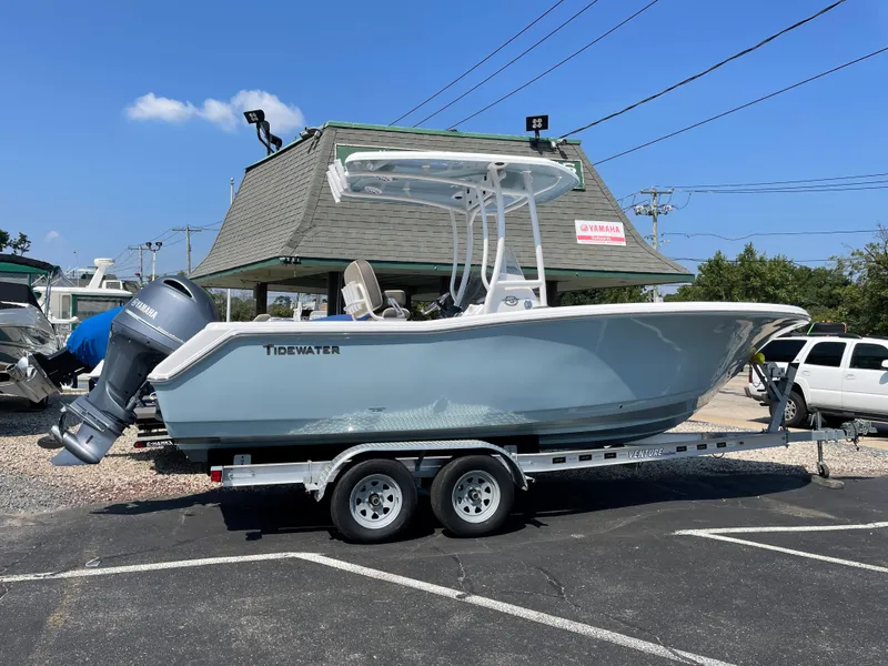 Slide: The Image of 2022 Tidewater 220 CC Adventure boat on trailer, parked outdoors under clear sky. - 0