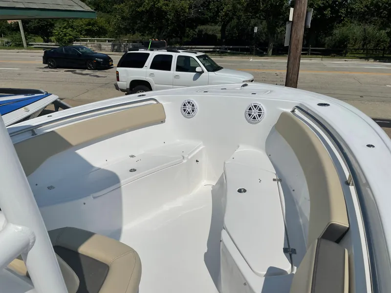 Slide: The Image of 2022 Tidewater 220 CC Adventure boat interior with seating and speakers, parked near vehicles. - 10