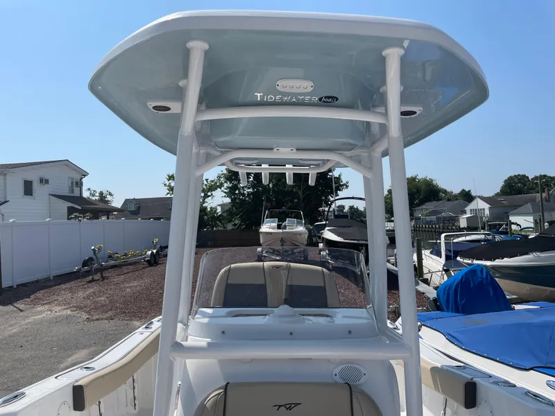 Slide: The Image of 2022 Tidewater 220 CC Adventure boat with T-top, docked in a sunny marina. - 17