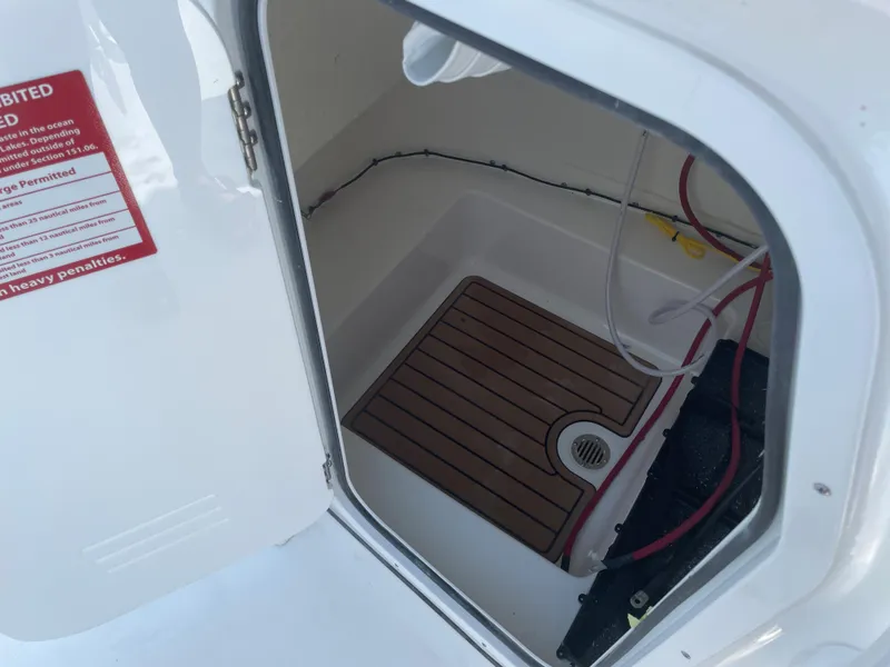 Slide: The Image of 2022 Tidewater 220 CC Adventure boat storage compartment with wooden flooring and wiring. - 18