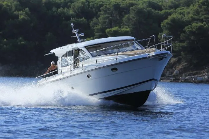 Slide: The Image of 2025 Nimbus 405 Coupé cruising on water with forested shoreline in the background. - 2