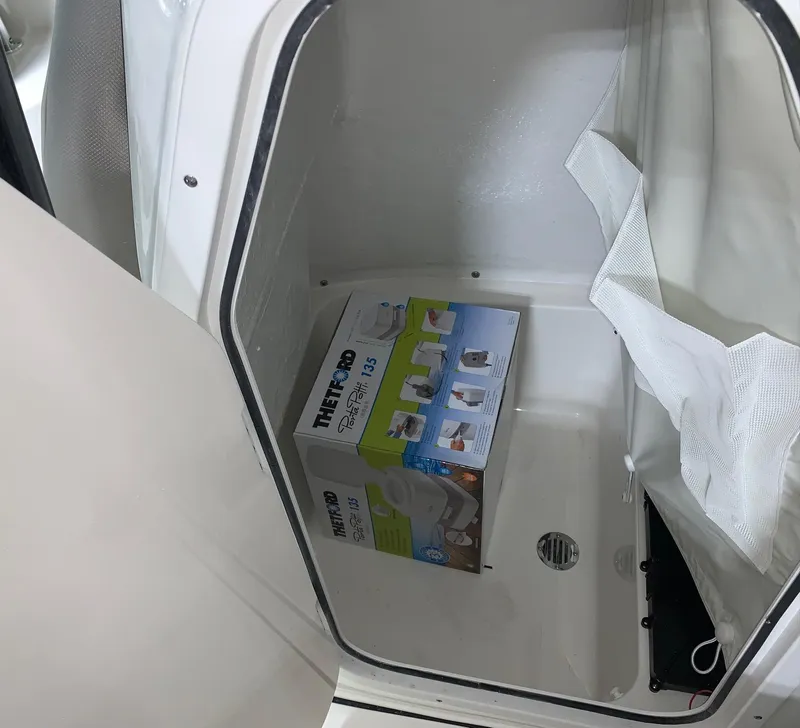 Slide: The Image of Storage compartment of 2024 Key West 203 FS boat with a Thetford Porta Potti box. - 6