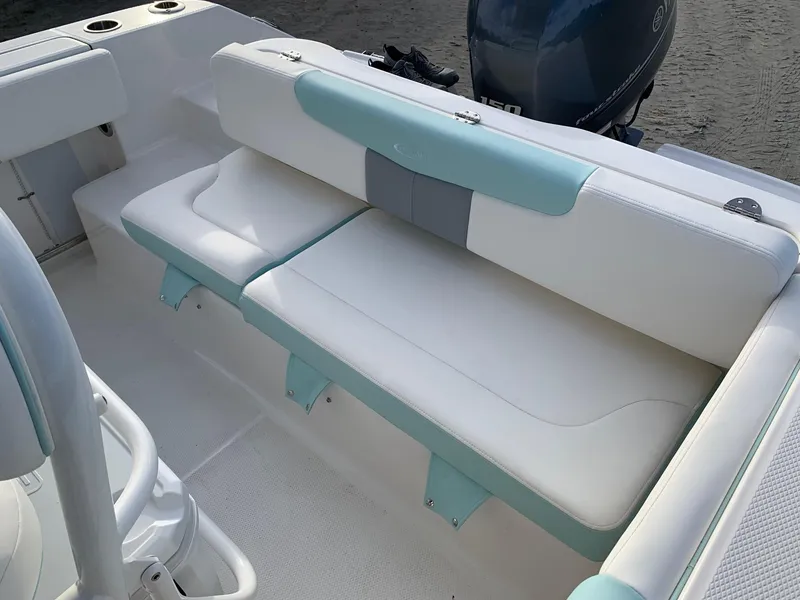 Slide: The Image of 2024 Robalo R202 Explorer boat interior seating with white and teal cushions. - 6