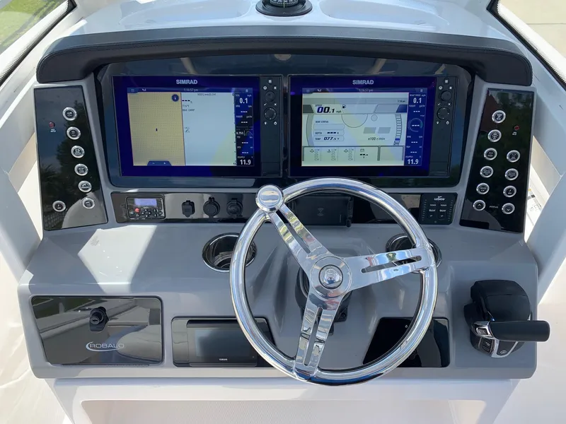 Slide: The Image of 2024 Robalo 266 Cayman boat dashboard with dual Simrad displays and chrome steering wheel. - 11