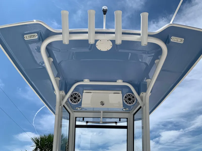 Slide: The Image of 2024 Robalo 266 Cayman T-top with rod holders and speakers against a blue sky. - 4