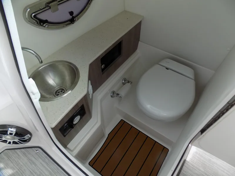 Slide: The Image of 2019 Regal 26 FasDeck boat bathroom with sink, toilet, and wooden floor mat. - 9