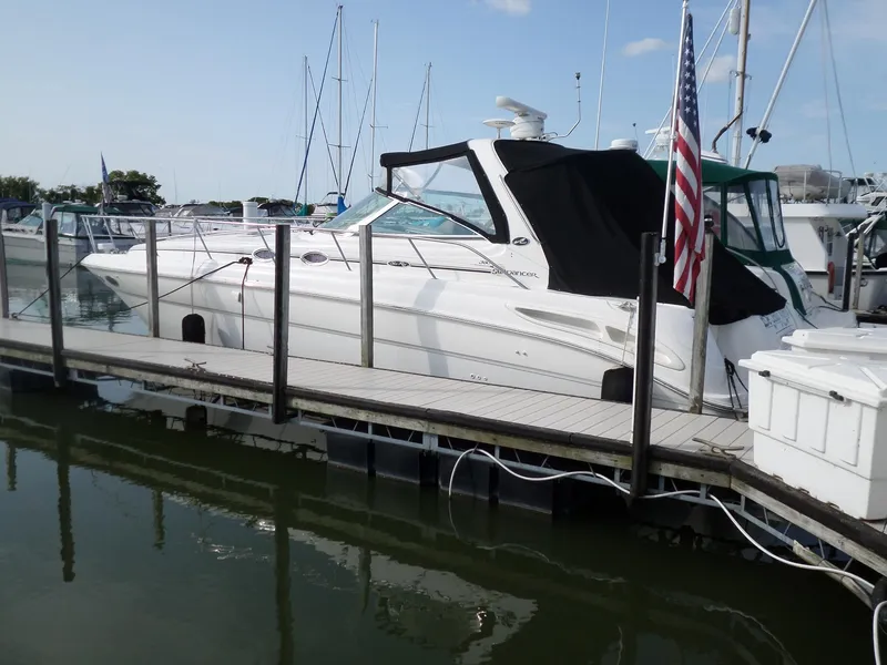Slide: The Image of 2003 Sea Ray 380 Sundancer docked with black canopy and American flag. - 2