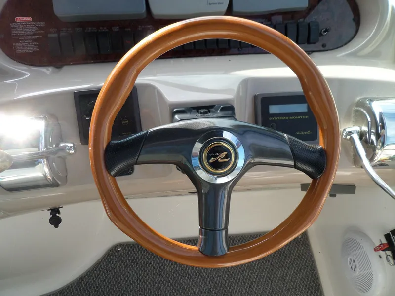 Slide: The Image of The image shows the steering wheel of a 2003 Sea Ray 380 Sundancer with wood trim. - 14