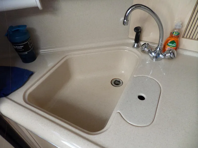 Slide: The Image of A sink with a faucet and cleaning supplies in a boat's galley. - 42