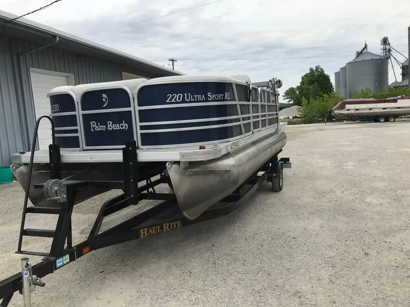 Slide: The Image of 2015 Palm Beach Ultra Sport 220 pontoon boat on trailer in outdoor setting. - 3