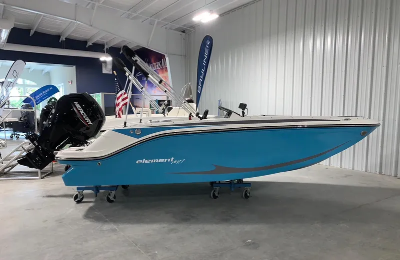 Slide: The Image of 2024 Bayliner Element M17 boat in showroom, blue hull, outboard motor. - 0
