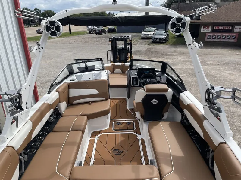 Slide: The Image of 2021 Malibu 22 LSV boat interior with tan and white seating, advanced dashboard, and wakeboard tower. - 5