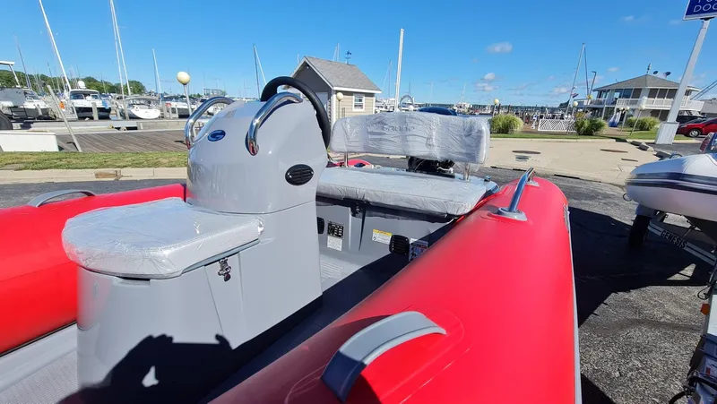 Slide: The Image of 2023 Grand Inflatables G380EF boat with red and gray seating, docked at a marina. - 13