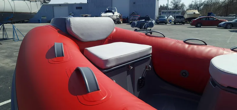 Slide: The Image of 2023 Grand Inflatables G380EF red inflatable boat with cushioned seating in a marina. - 8